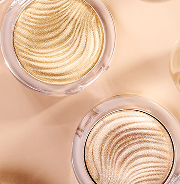 Two gold compact powders with a close-up view on a beige background